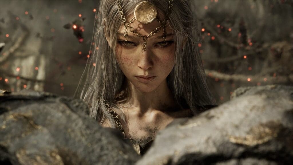 Nodusfall character with long silver hair and ornate head jewelry stares forward amid rocky ruins and glowing embers.